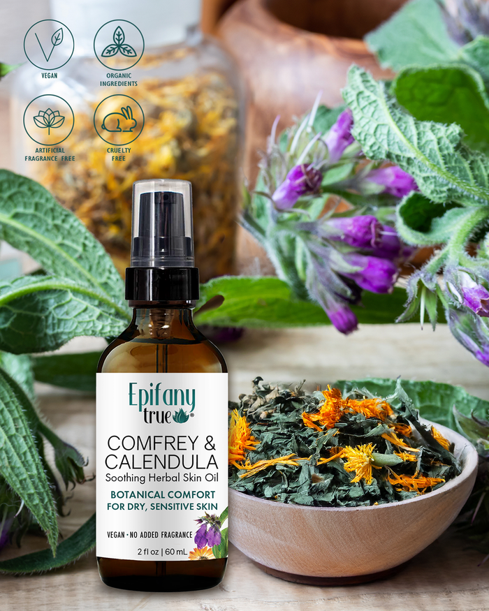 Bottle of Epifany Comfrey & Calendula Herbal Skin Oil with botanical elements on a wooden surface.