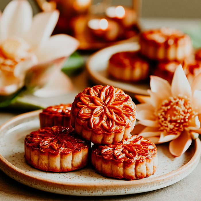 Mooncakes on a plate with flowers and candles in the background