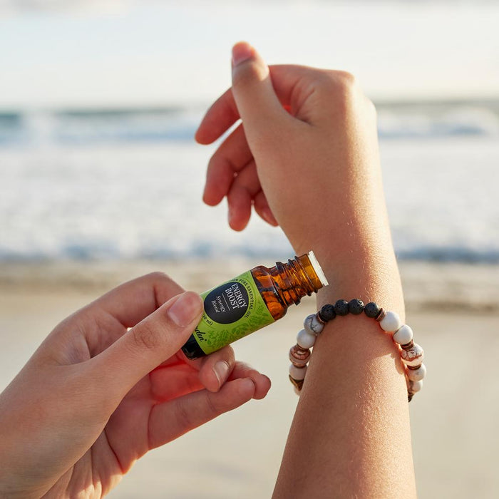Person applying Energy Boost synergy blend to the The Cayman Bracelet by Edens Garden on the beach